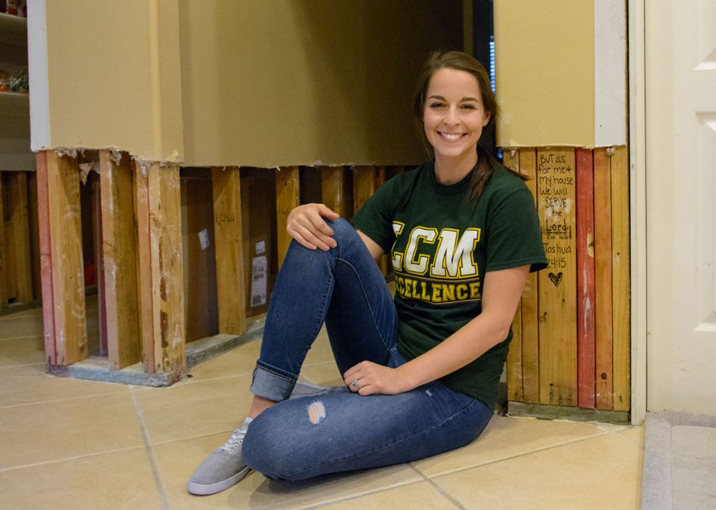 Taylor Willis, a teacher in Orange, Texas, sits in her house that is in the process of being repaired after Hurricane Harvey flooded her neighborhood. The Bible verse to the right of her is one of many written throughout her house by volunteers that helped remove dry wall. Photo by Marlee Crawford