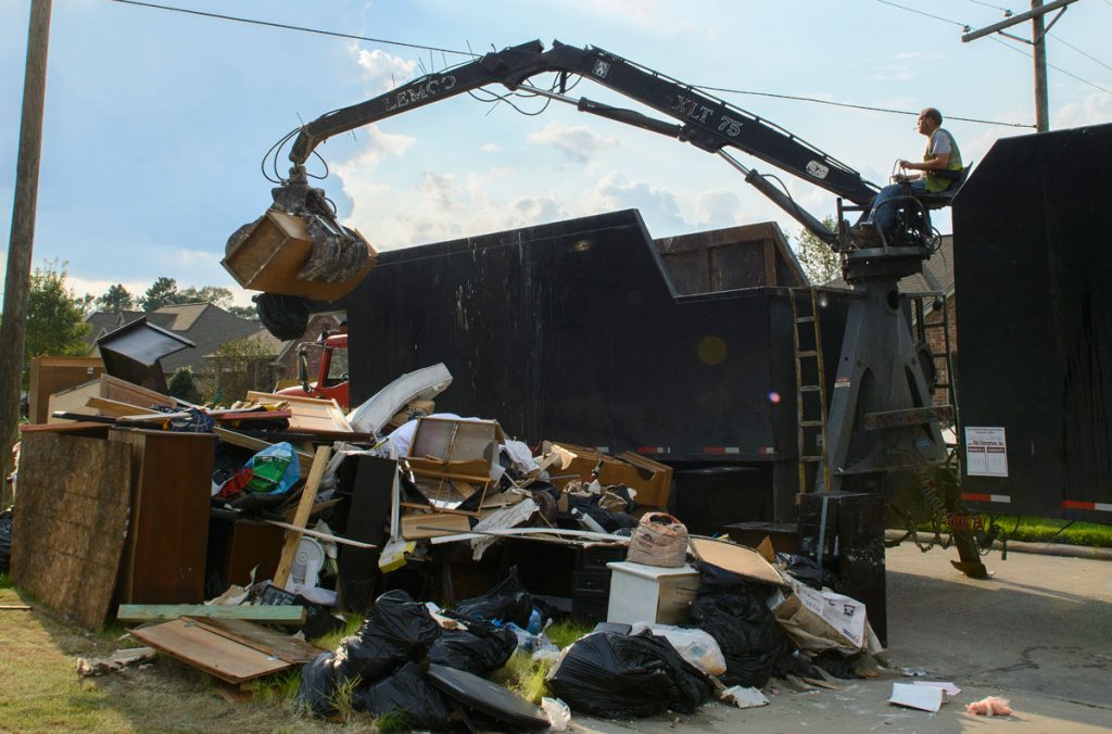 A FEMA employee scoops up soaked and water-damaged debris from Willis' neighbor's yard to carry away in a dump truck. Photo by Marlee Crawford