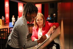 Student signs a book on a podium.