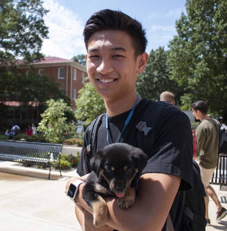 Shimba Ochiai holds a puppy outside the student union as part of the Welcome Week festivities. Welcome Week events are hosted by the Student Activities Association. Photo by Billy Schuerman.